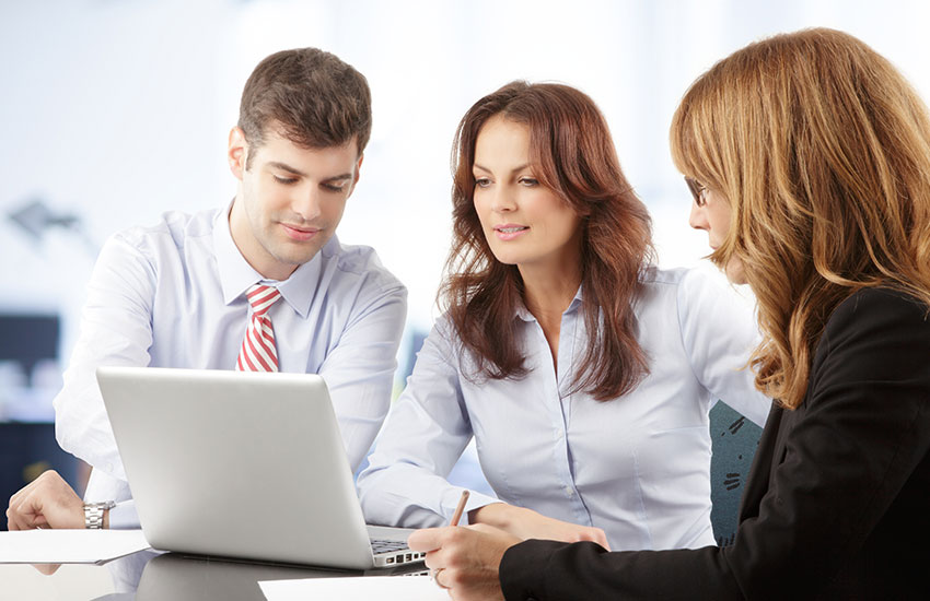 Agents sitting at table looking at laptop
